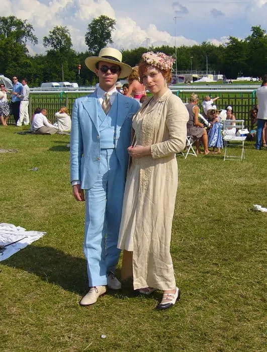 Andrea Sperelli in a light blue suit posing with a person in a period dress