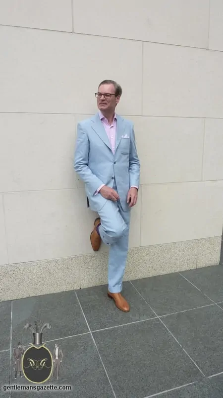 Herbert Strickler poses leaning against a wall in his sky blue Irish linen suit