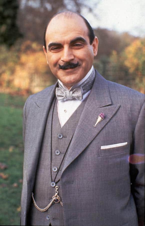 Hercule Poirot in a gray three-piece suit, gray polka dot bow tie, albert chains with Boutonniere Vase