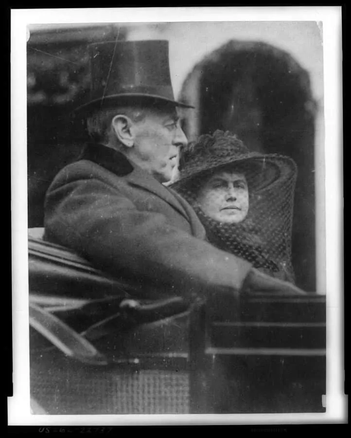 Woodrow Wilson and wife riding in back seat of a carriage to second inauguration with top hat and velvet collar on March 5, 1917