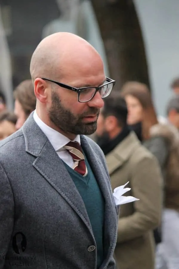 A man wearing Gray diagonal twill jacket with knit vest and striped silk tie