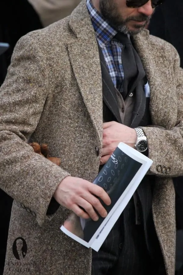 Photograph of a man wearing Plaid cotton flannel shirt, flannel chalk stripe suit, knit cardigan and donegal tweed overcoat