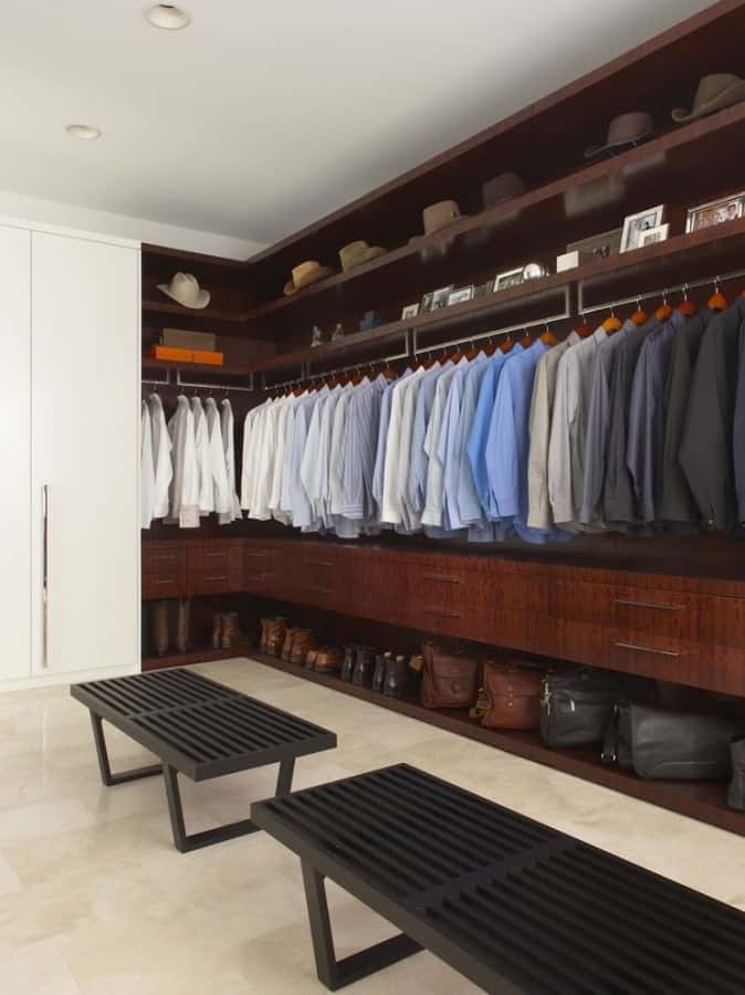 Men's closet with hat storange on top and too much spacing between shirts