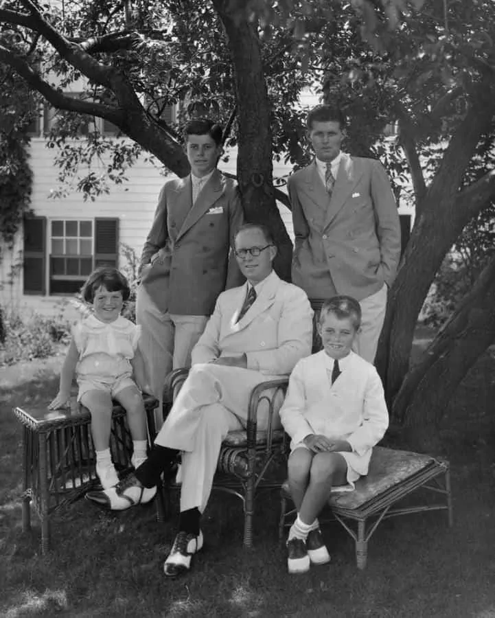 Young JFK with double breasted combination & collar pin with father Joe and siblings