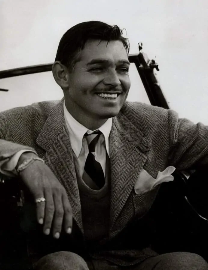 Clark Gable all smiles in a herringbone jacket with v-neck sweater and a stripe tie