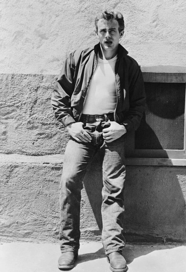 James Dean in Rebel Without a Cause, sporting his iconic ensemble of red Harrington jacket, white T-shirt, jeans, and boots.