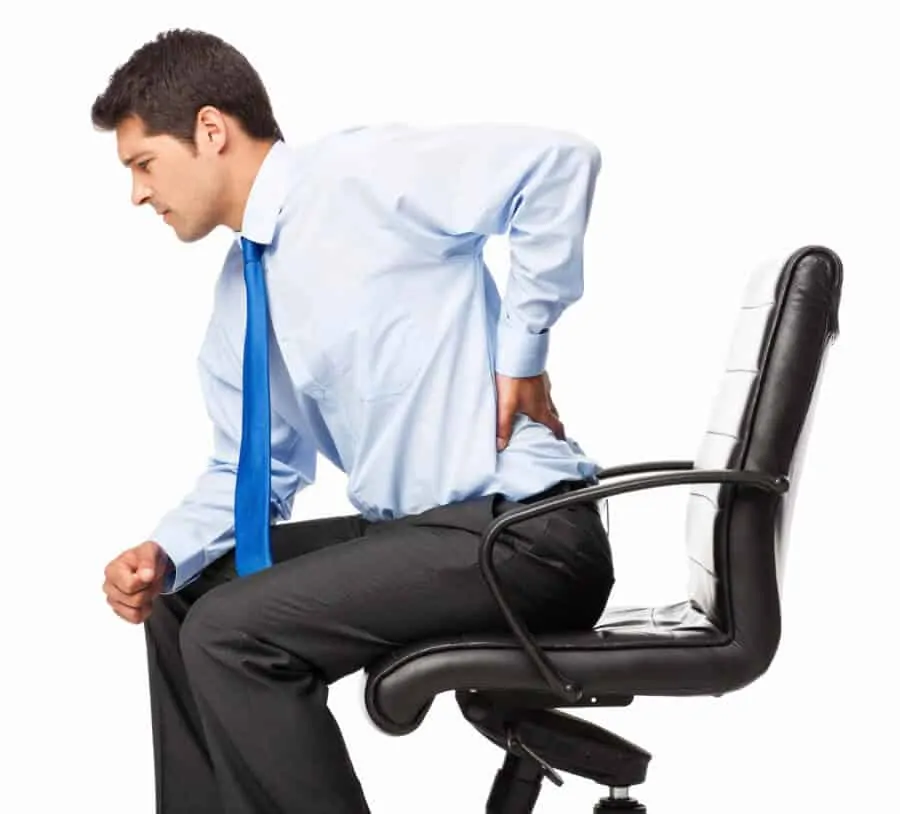 Young businessman with backache sitting in an office chair. 