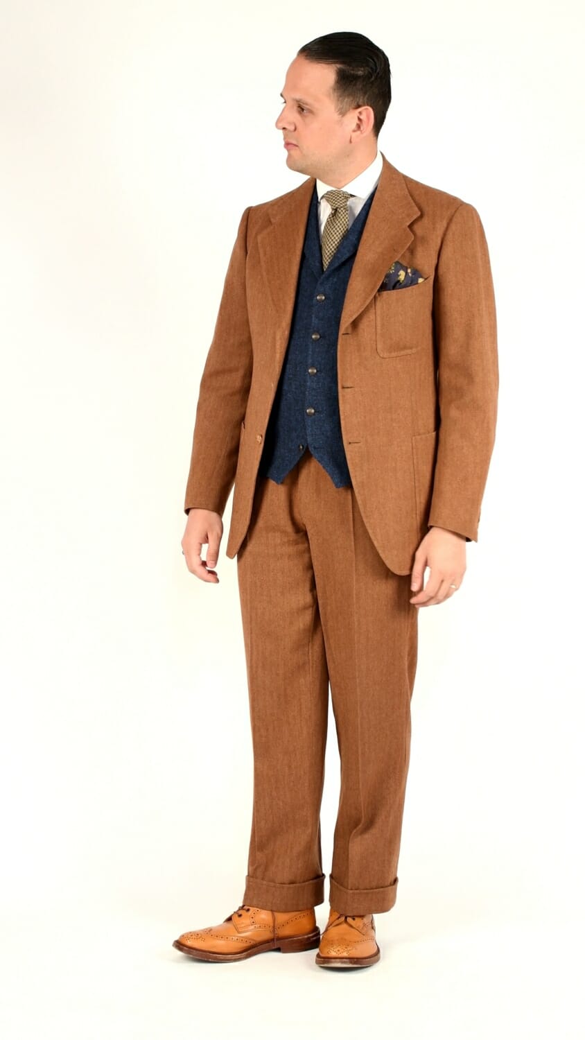 Sven Raphael Schneider wearing a rust-colored, single-breasted herringbone suit with a contrasting vest and tan full brogue boots