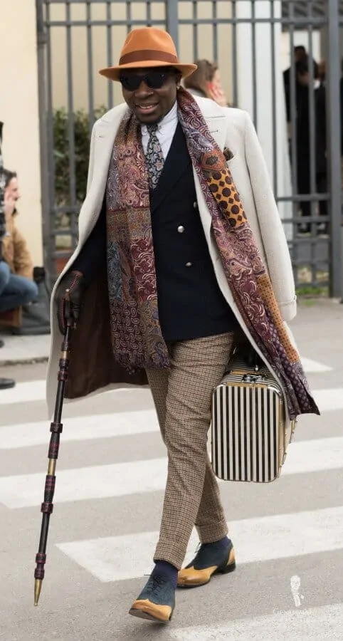 Flamboyant outfit with bold colors, patterns, patchwork scarf and cane