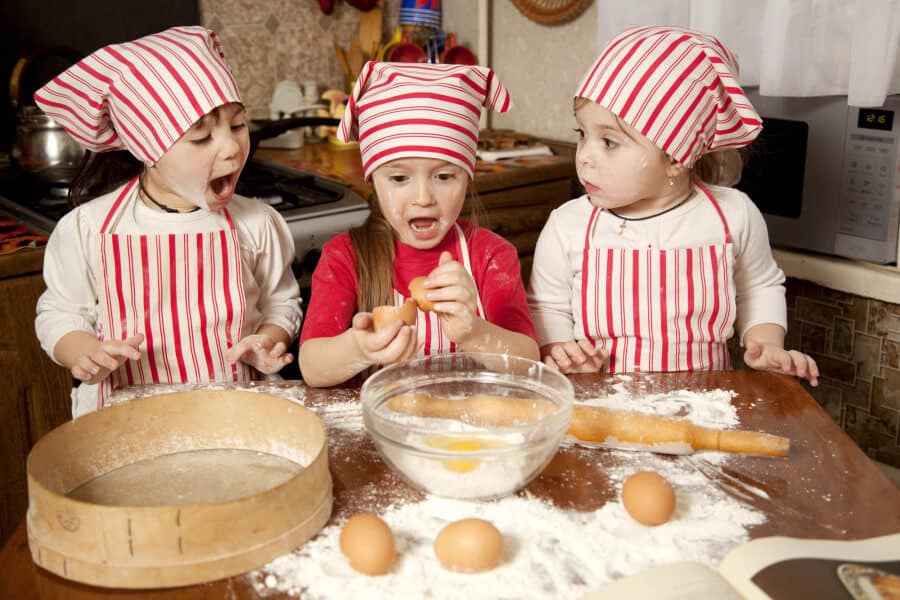 Three little chefs enjoying in the kitchen making big mess. Litt