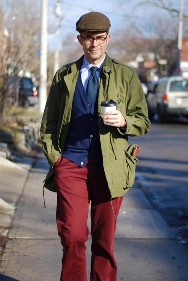 Pedro during fall autumn season wearing red slacks, blue knit cardigan, green madder tie, striped shirt and olive green jacket