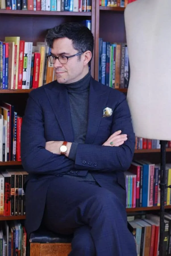 Pedro in dark suit with grey turtleneck sweater, wristwatch and signet ring