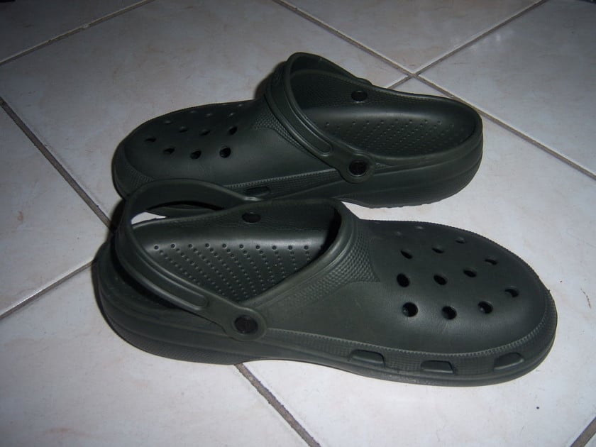 A pair of dark green crocs boat shoes