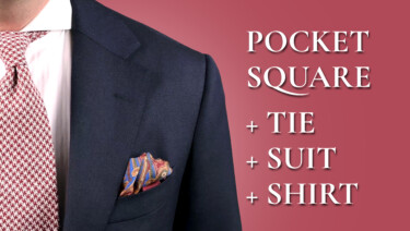 red and white houndstooth tie, navy suit, pocket sqaure and white shirt combination on red background. Text reads: "Pocket Square + Tie + Suit + Shirt"