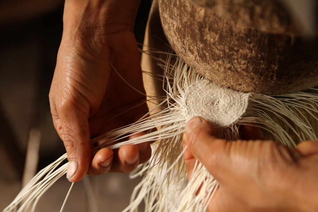 Hand weaving the crown of a Panama hat