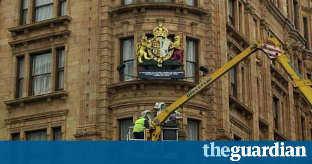 A man removes the Royal Warrants from Harrods façade