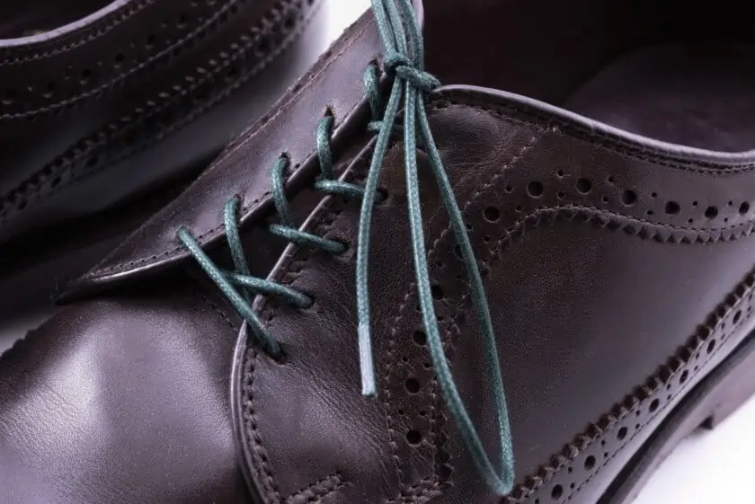 Dark green shoelaces worn on a dark leather shoe