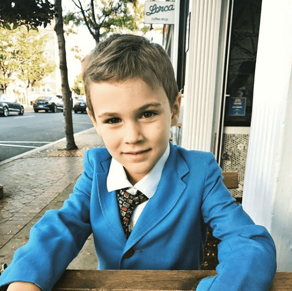Emmett Emmett wearing a bright blue jacket and tie with a geometric print that is appropriate to his age.