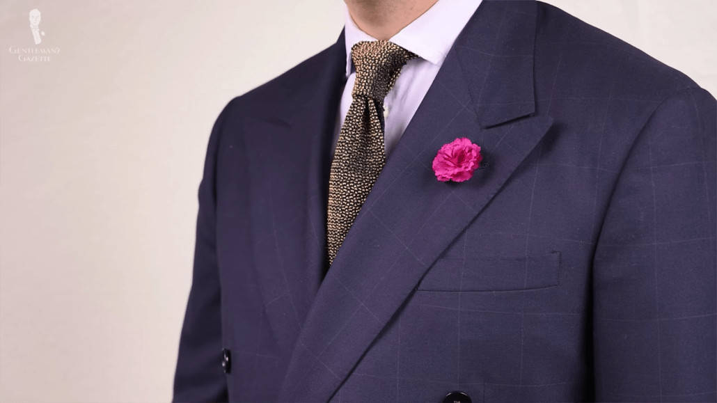 Navy suit jacket accessorize with a knit tie and pink boutonniere