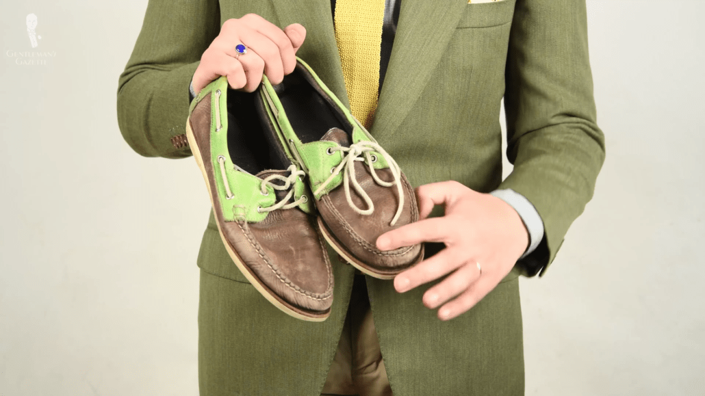 Worn navy and light green boat shoes with white leather laces 