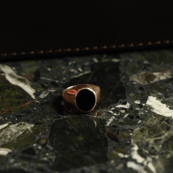 A 14 karat rose gold ring with an oval Onyx
