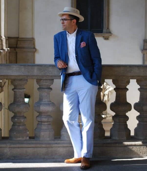 Pedro Mendes in an open blue jacket with a pink flowery pocket square, a white button-down shirt, sky blue chinos and tan oxfords