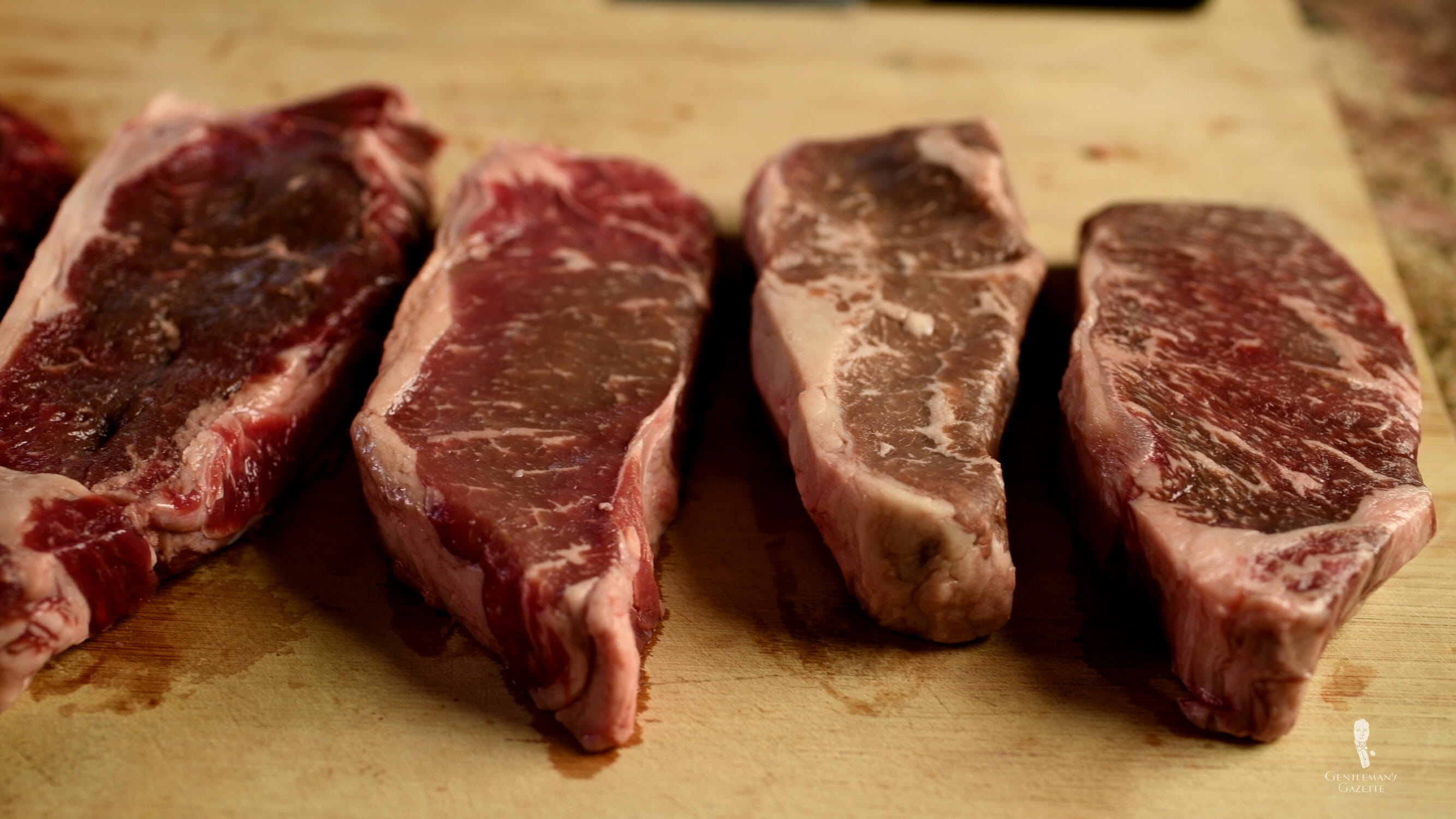 New York Strip aka Kansas City Strip Steak cuts with different degree of marbling - From Right to Left - Akaushi, Prime, Select, Grass Fed