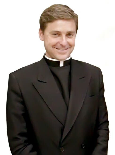 Author and commentator Fr. Jonathan Morris wearing a rabat (clerical dickie) with a double-breasted black jacket