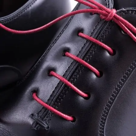 Red shoelaces worn on a black leather shoe