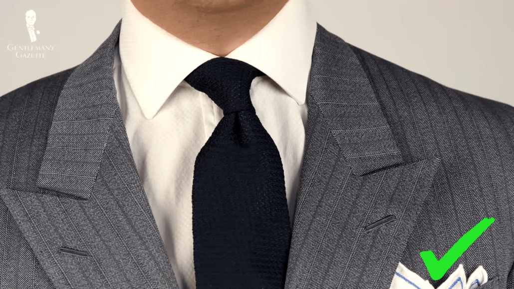 This striped grey suit benefits from a more casual knit tie in navy and a pocket square with colorful edging.