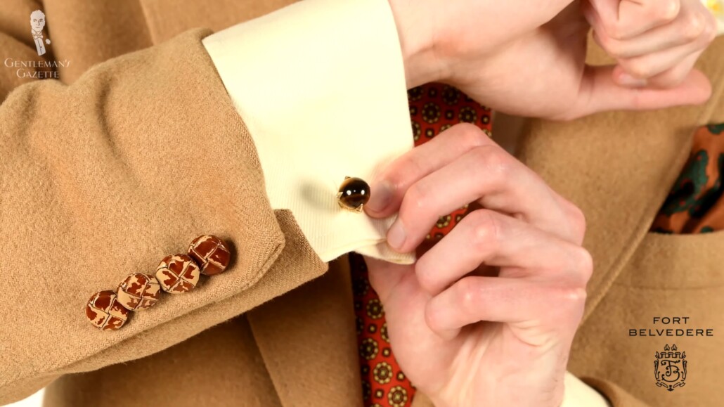 Preston wears a pair of cufflinks that matches with the general tone of the outfit.