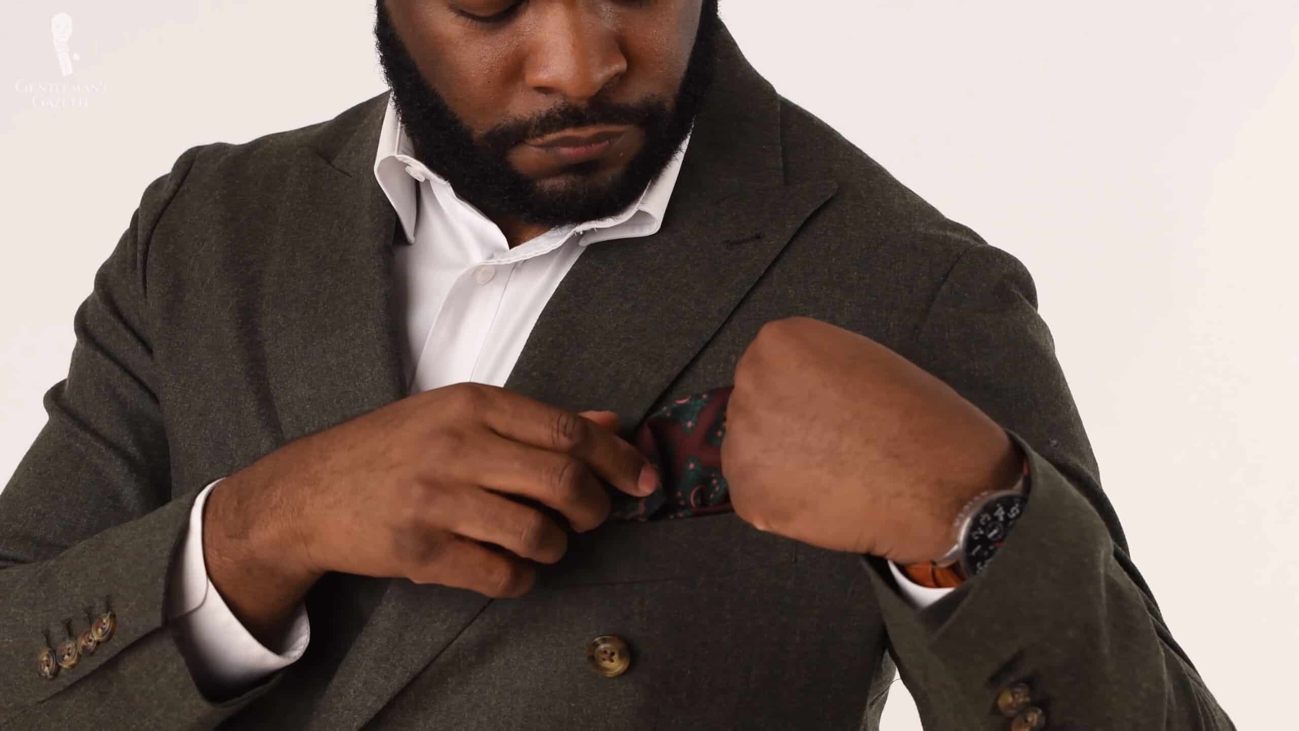Kyle wearing an olive green suit jacket, Invicta watch, and Fort Belvedere pocket square