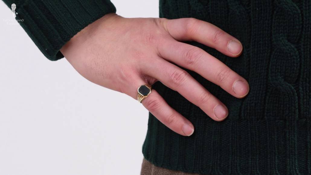 A photograph of a hand on the hip, with a pinky ring on the finger 