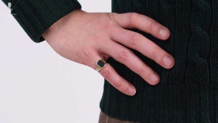 A gold pinky ring with a green stone