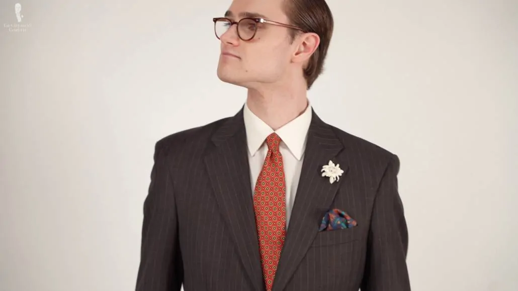 Preston in a dark brown patterned suit jacket, white collared shirt, and accessories from Fort Belvedere.
