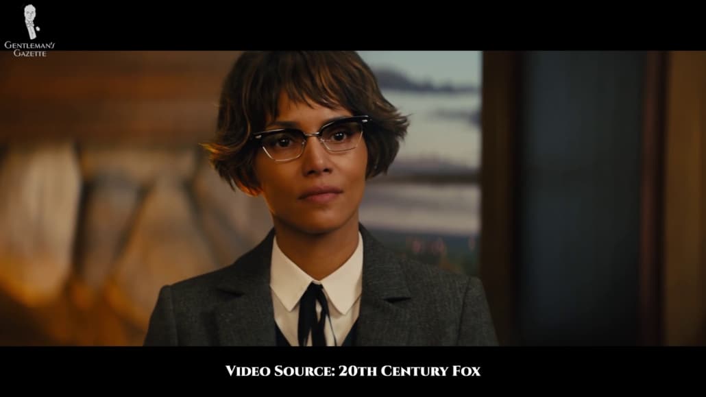 Ginger Ale in a standard Statesman-styled ensemble of jeans, charcoal western-style jacket, and a v-neck sweater. She also sports a clubmaster glasses in a more feminine style. 