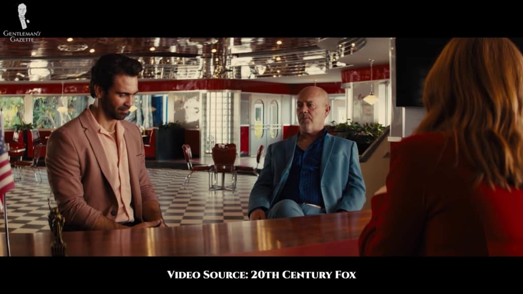 The henchman Charles wearing a powder blue suit with narrow peak lapels and a blue striped shirt.