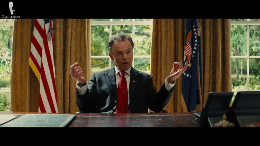 The president of the United States wearing a black suit, white barrel cuffed shirt, and red solid tie.