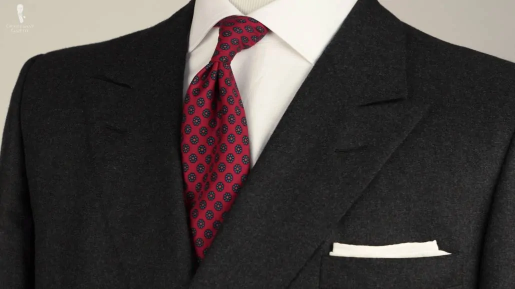 A charcoal gray suit with a rMadder Silk Tie in Dark Ruby Red and white pocket square combination. 