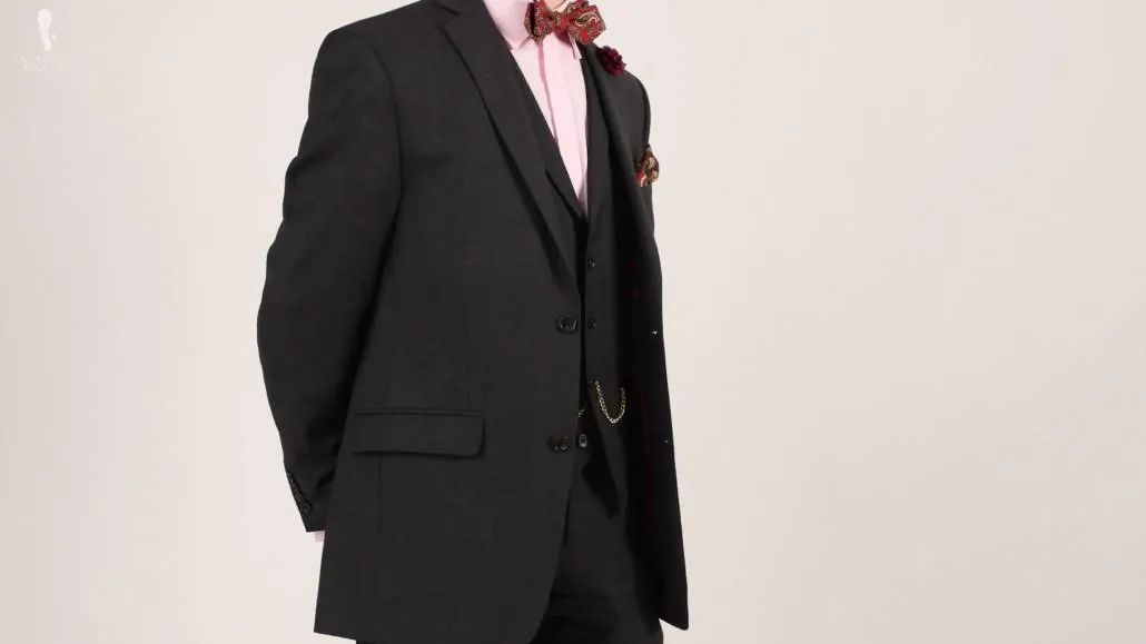 A three-piece charcoal gray suit combined with red- toned accessories 