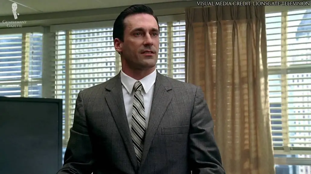 Don Draper in a light gray suit, white dress shirt with point collar, and stripe patterned tie. 