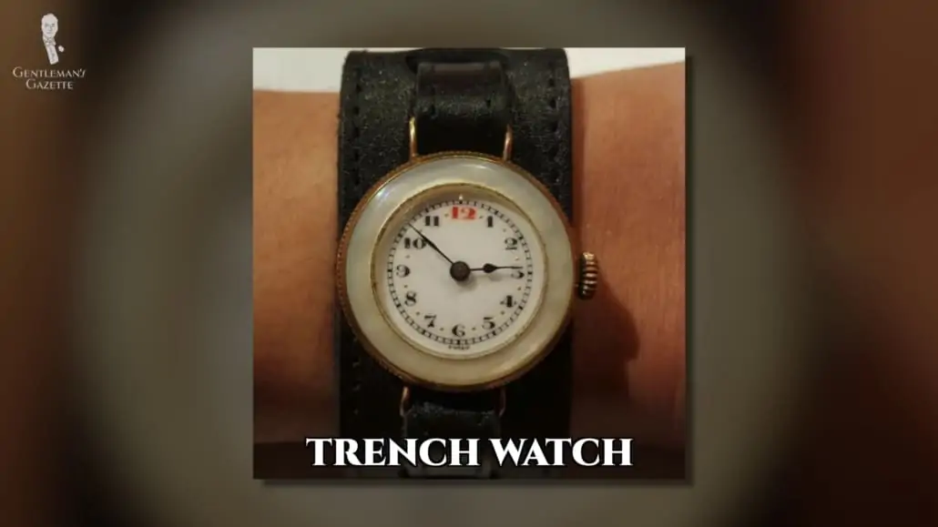 An old trench watch with a black leather strap.