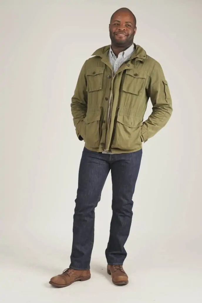 Smiling Kyle wearing a green jacket, dark wash Levi's 501 jeans, and brown Red Wing Boots