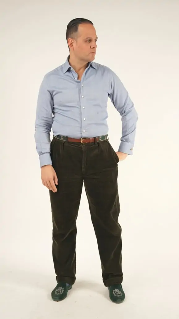 Raphael wearing his made-to-measure shirt from 100 hands in a bluish gray color, dark brown corduroy pants, brown belt, and green velvet Albert slippers with Fort Belvedere logo.