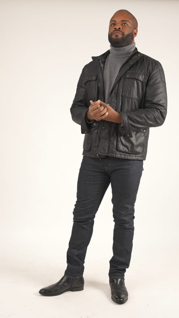 Kyle sporting a black waxed cotton jacket, gray turtleneck sweater and denim jeans.