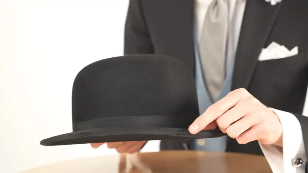 Preston pointing at a bowler hat's defect. 