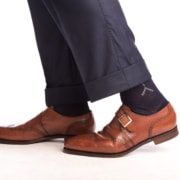 A pair of navy socks with clocks worn with brown shoes