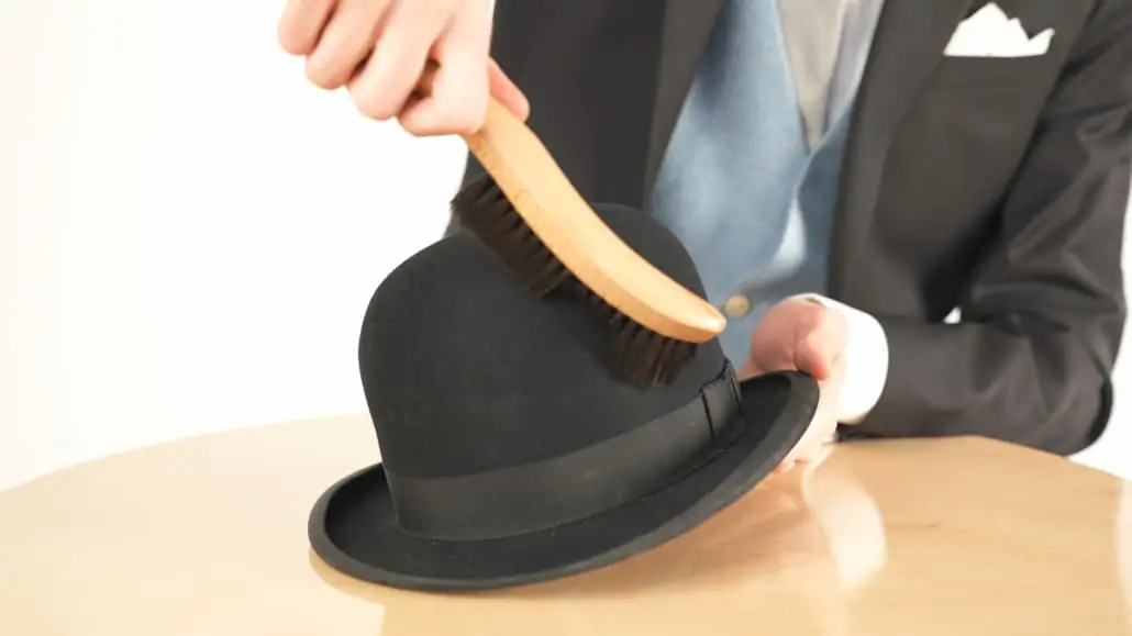 Preston using a hat brush to keep his bowler hat looking good.