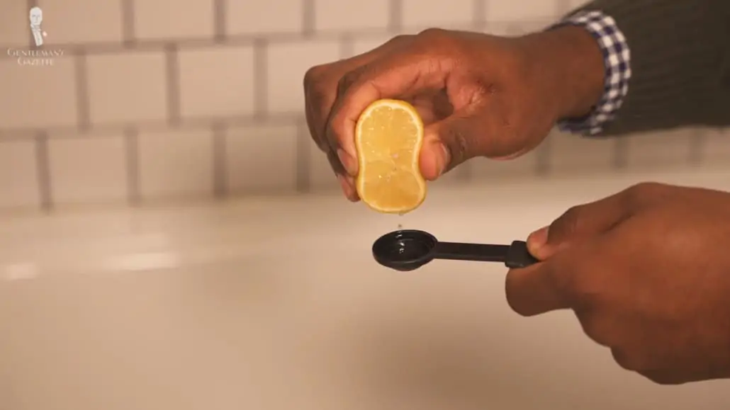 Kyle squeezing half a lemon into a measure teaspoon.