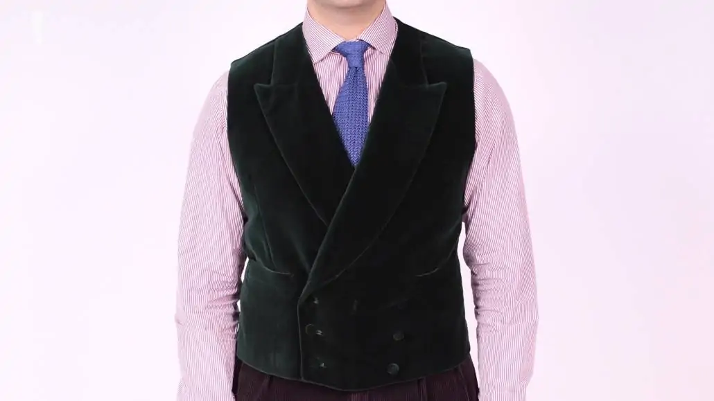 Raphael wearing a black double-breasted velvet vest, pink long sleeveed shirt, and blue knit tie